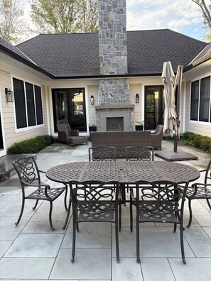 A patio with a stone fireplace, outdoor seating, and a table with chairs. - Ryder cup rental NEW CUSTOM 3 BEDROOM RANCH 7.2 miles from bethpage black course (Huntington)