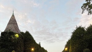 Une route pavée bordée d’immeubles aux murs recouverts de lierre et d’une tour surmontée d’un toit conique.