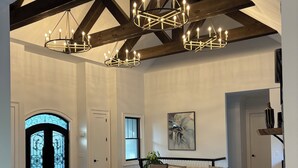 Un vaste salon doté d’un haut plafond, de poutres apparentes et d’un grand lustre.
