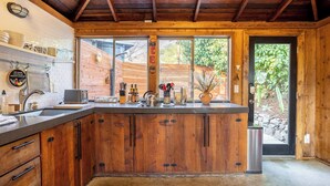 Eine Küche mit Holzausstattung, einer Edelstahl-Spüle und einem Fenster mit Blick auf einen Garten.