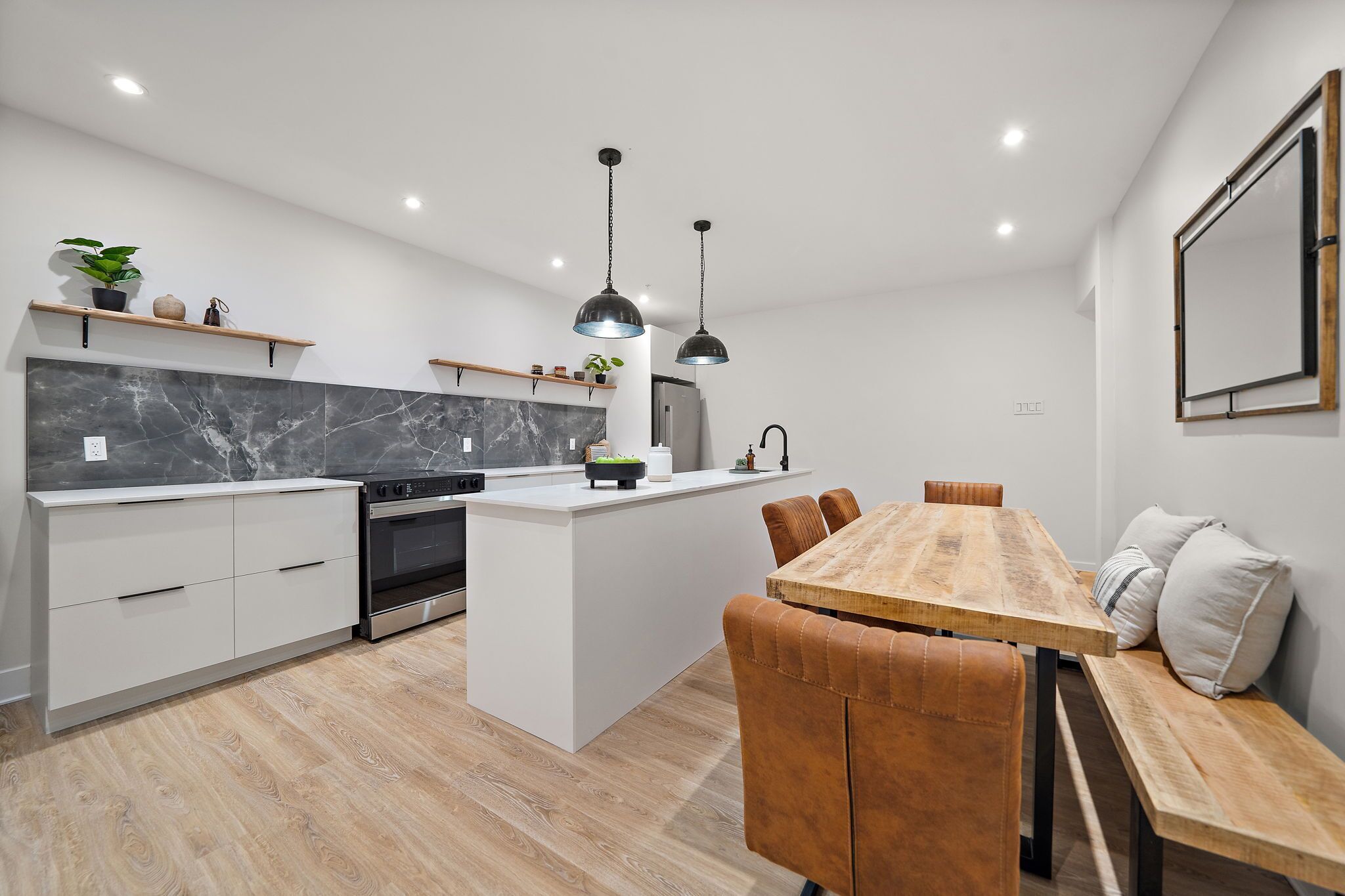 Een moderne keuken met een centraal eiland, een houten eettafel en bruine leren stoelen.