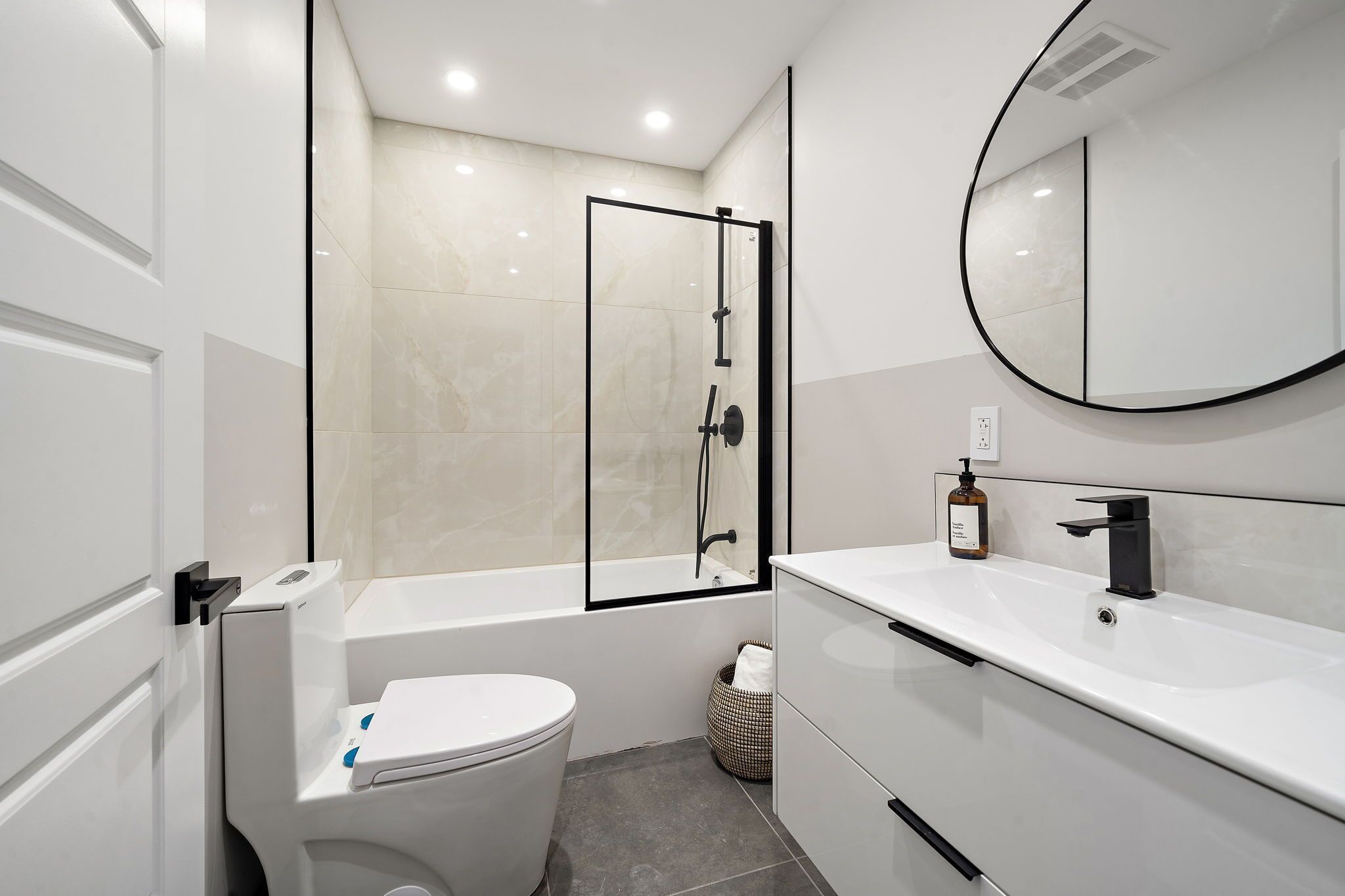 A modern bathroom with a toilet, a bathtub, a shower enclosure, a sink, and a mirror.