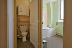 A bathroom with a toilet, a sink, and a trash can.