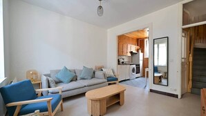 A living room with a sofa, chairs, a coffee table, and a kitchen area with a washing machine. - Hiram - seaside (Fécamp)