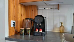A kitchen with a coffee maker, jars, and a bottle. - Hiram - seaside (Fécamp)