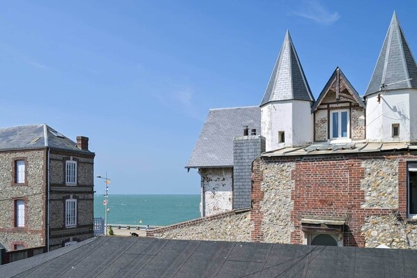A coastal building with a stone facade, multiple pitched roofs, and a view of the sea.