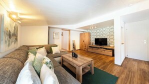 Un salon moderne avec un canapé d’angle, une table basse en bois, un téléviseur à écran plat et un meuble en bois.