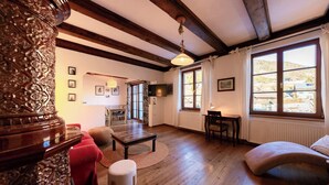 Amplia sala de estar con pisos de madera, chimenea, comedor y ventanas grandes con vistas al exterior.