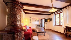 Amplia sala de estar con piso de madera, un sofá rojo, una mesa de centro y un gran ventanal con cortinas.