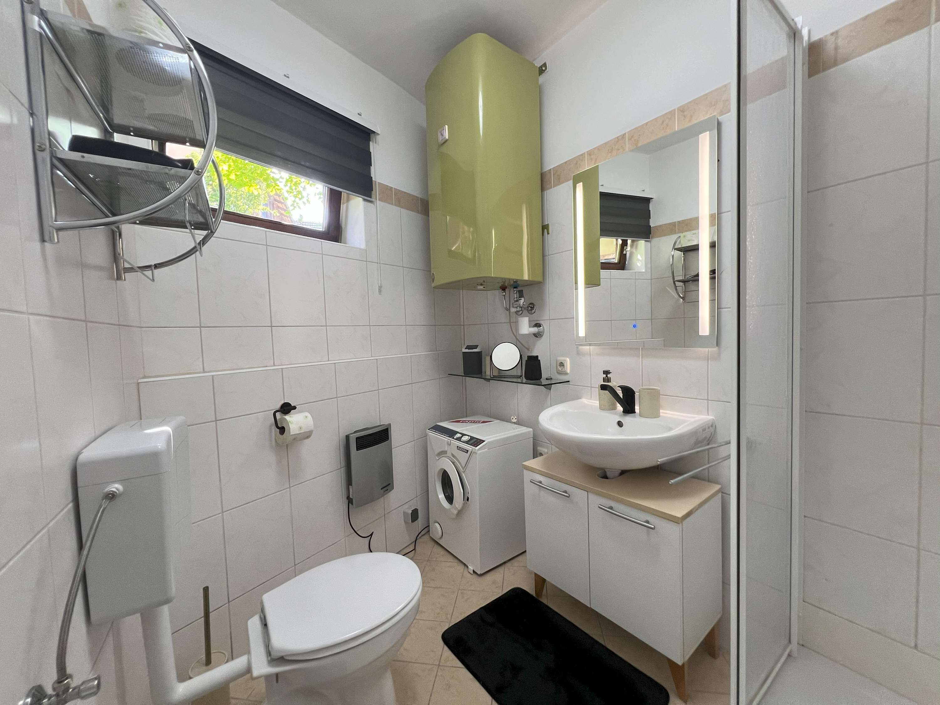 A compact bathroom with a toilet, washing machine, and sink.