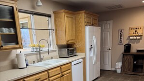 Una cocina con armarios de madera, un refrigerador blanco, un tostador y un letrero que dice 'Coffee Bar'.