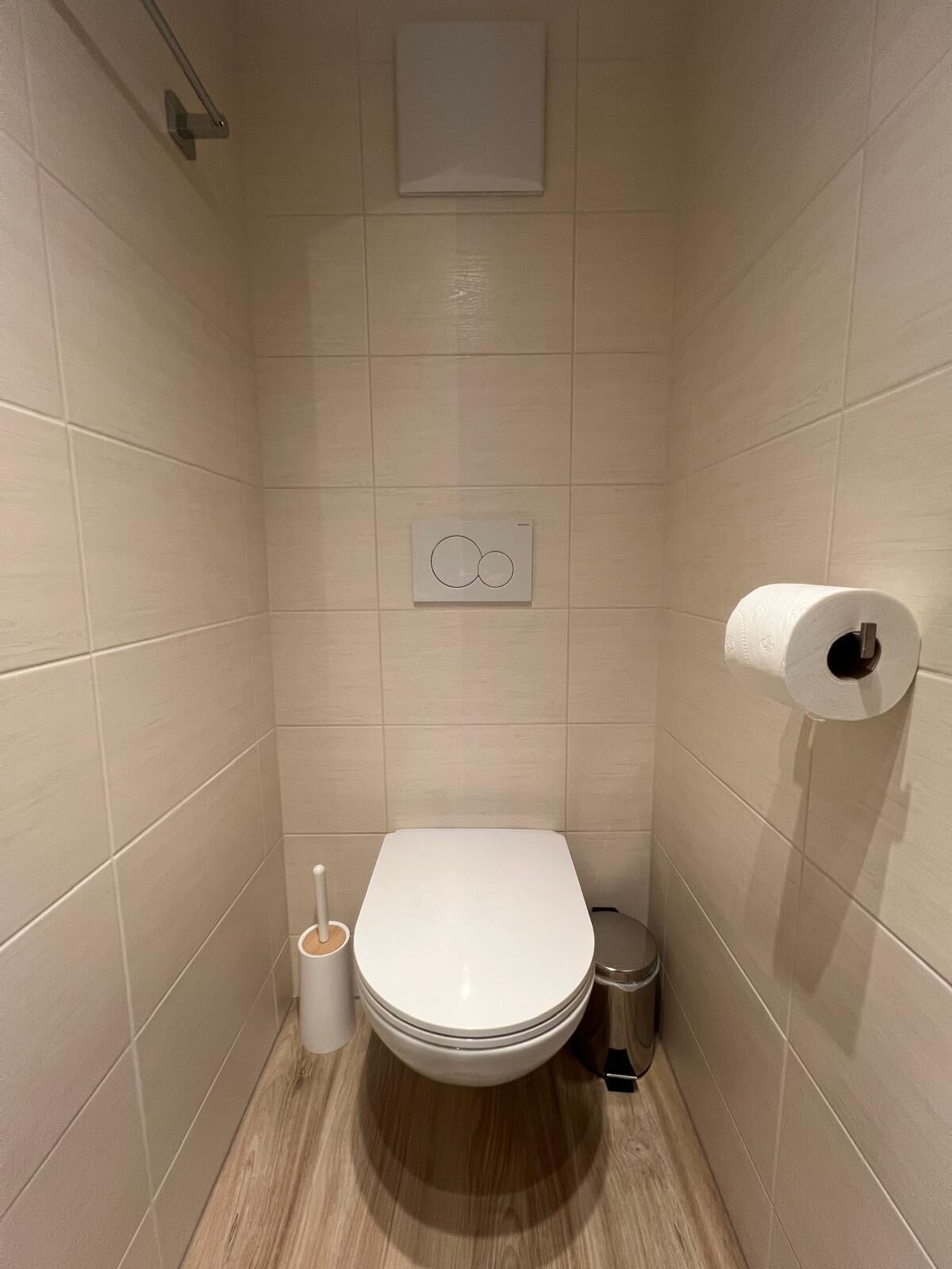 Une petite salle de bain moderne équipée de toilettes, d’un bidet et d’un porte-rouleau de papier toilette.