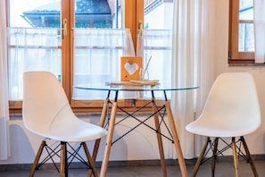 Ein Zimmer mit zwei weißen Stühlen, einem Glastisch und einem herzförmigen Holzobjekt auf dem Tisch.
