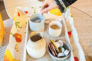 Una bandeja con tres tazas, un tarro y un recipiente con aperitivos sobre una mesa.
