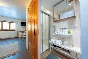 Ein modernes Badezimmer mit Glasdusche, weißem Waschbecken und einem Holzschrank.