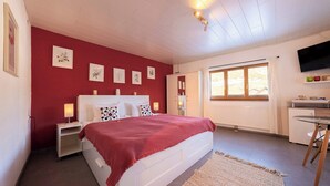 A bedroom with a bed, bedside tables, a TV, and a window. - Krokus Studio | Relax & Natur | Parking | Bikes (Altaussee)