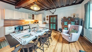 A dining area with a wooden table set for four, a rustic ceiling, and a vintage armchair. - Strauss Suite | Kitchen | Parking | Garden (Altaussee)