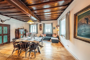 A dining area with a wooden table and chairs, a sofa, and a painting on the wall.