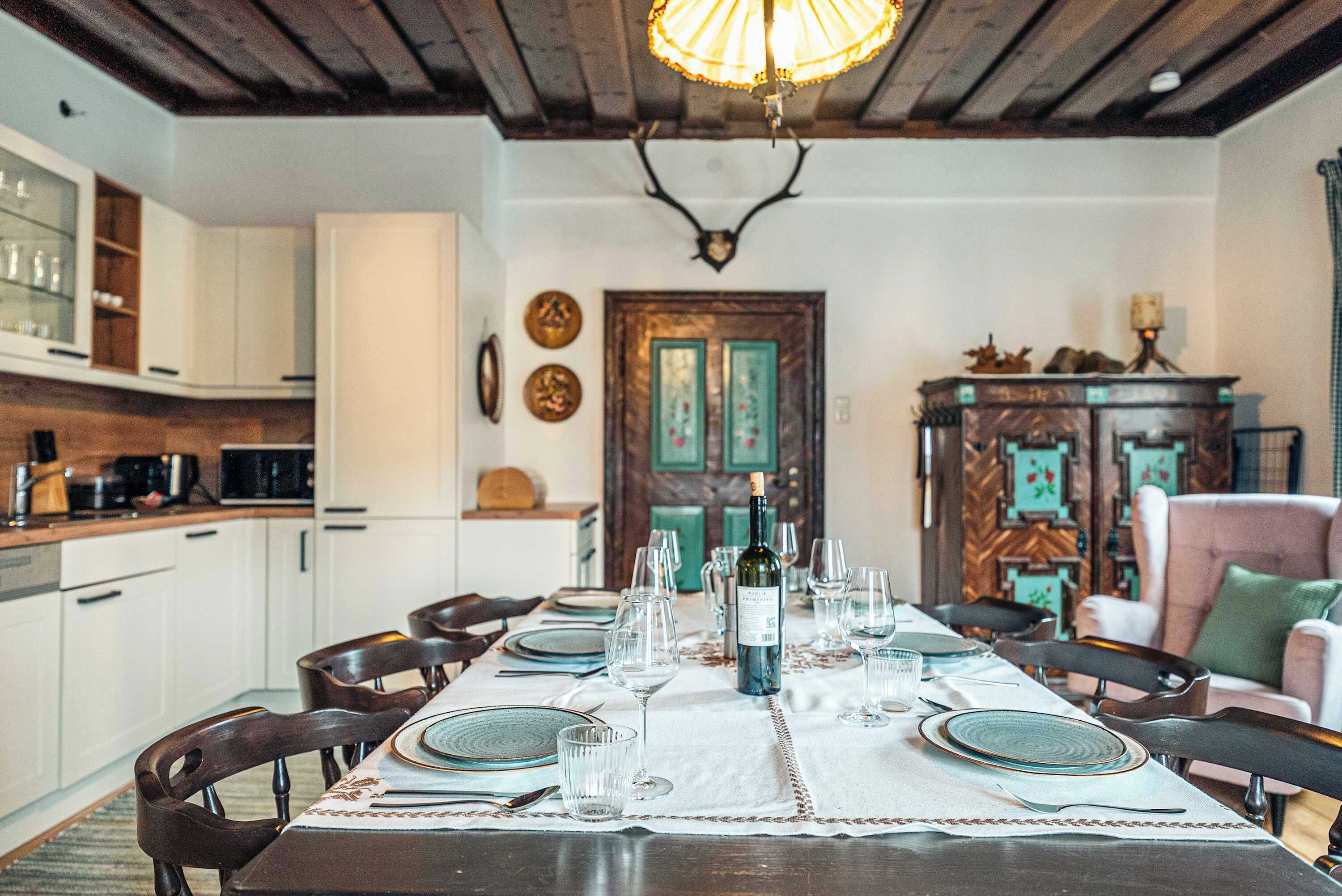 Une salle à manger avec une table dressée pour six personnes, un lustre et un plafond en bois.