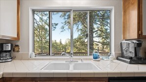 A kitchen with a large window, a double sink, and a coffee maker. - 5 Mi to Lake Arrowhead Village: Cabin w/ Game Room (Lake Arrowhead)