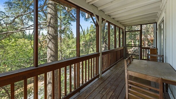 A wooden deck with a railing, a table, and chairs. - 5 Mi to Lake Arrowhead Village: Cabin w/ Game Room (Lake Arrowhead)