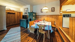 Ein gemütliches Zimmer mit einer Holzbänkl, einem Tisch mit Tischdecke, einer hängenden Leuchte und einem kleinen Kühlschrank.