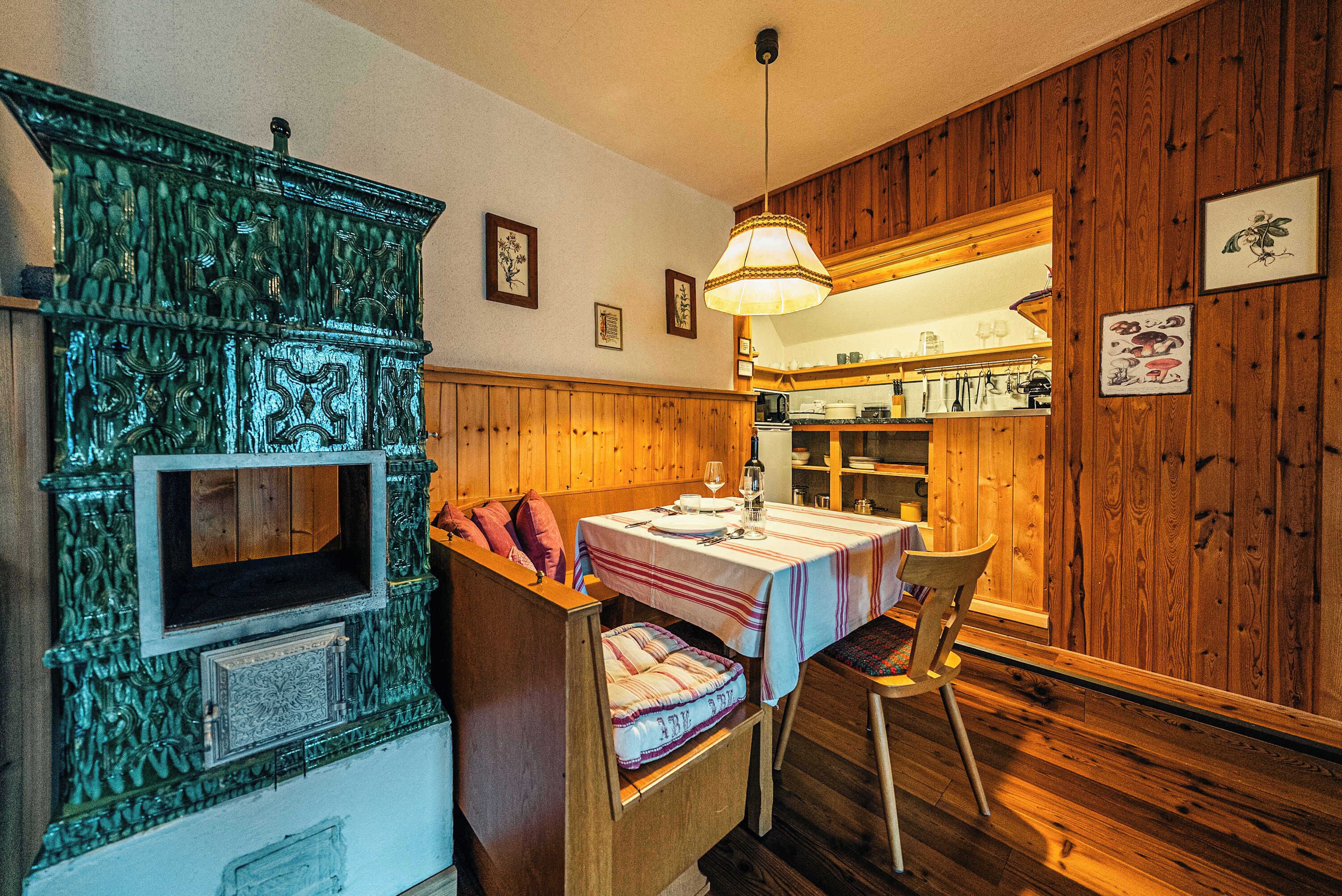 A wooden interior with a dining table, bench, and a decorative cabinet.