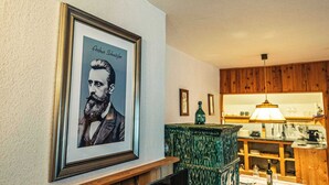 Ein gerahmtes Porträt an der Wand, ein Holzkabinent und ein Tisch mit einer Lampe.