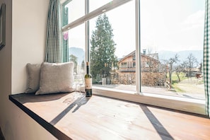 Ein Zimmer mit einem großen Fenster, einer hölzernen Bank und einer Weinflasche.