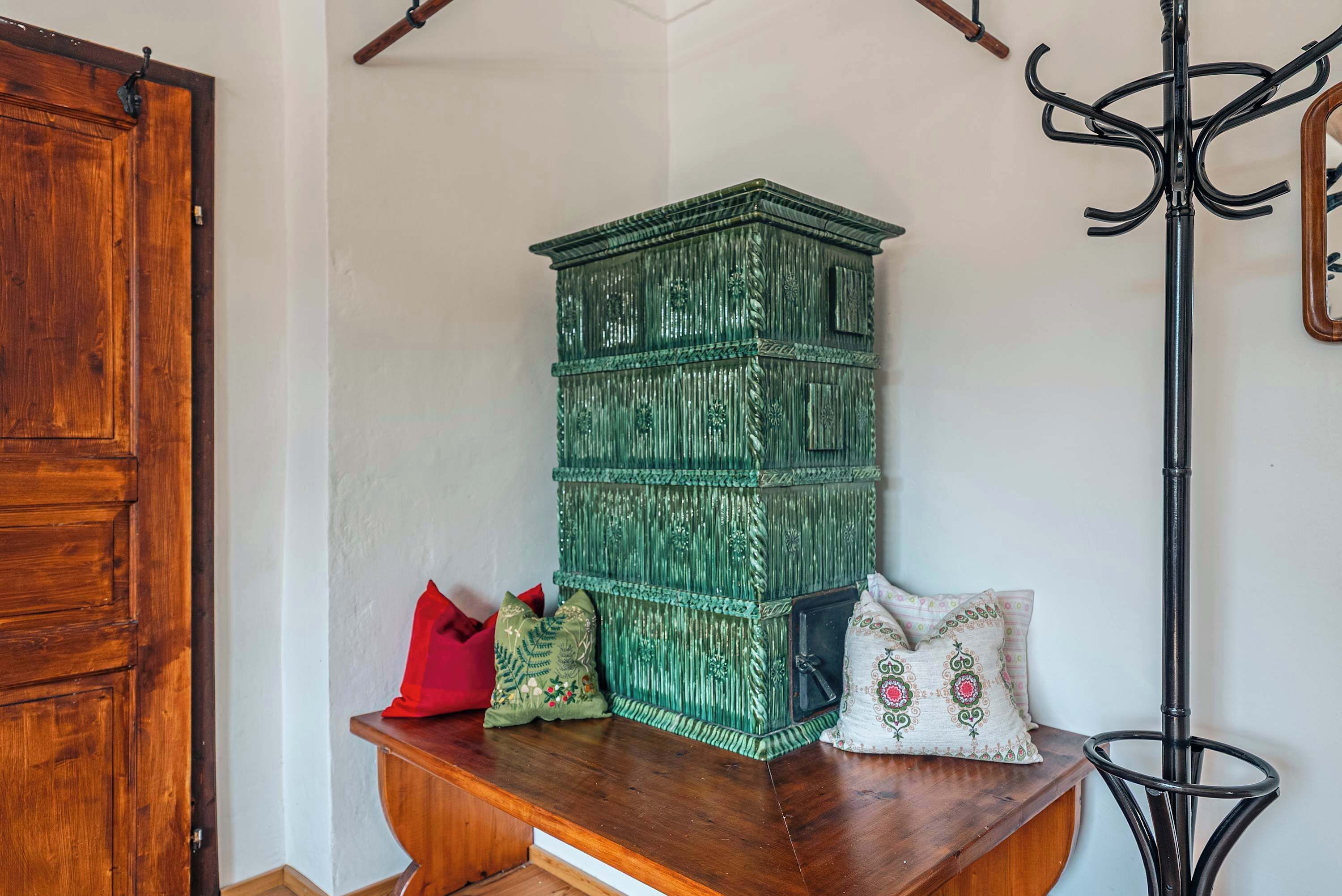 A wooden bench with a green chest of drawers and a coat rack.