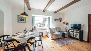A dining area with a table set for four, a sofa, a television, and a window with a view of the outside.