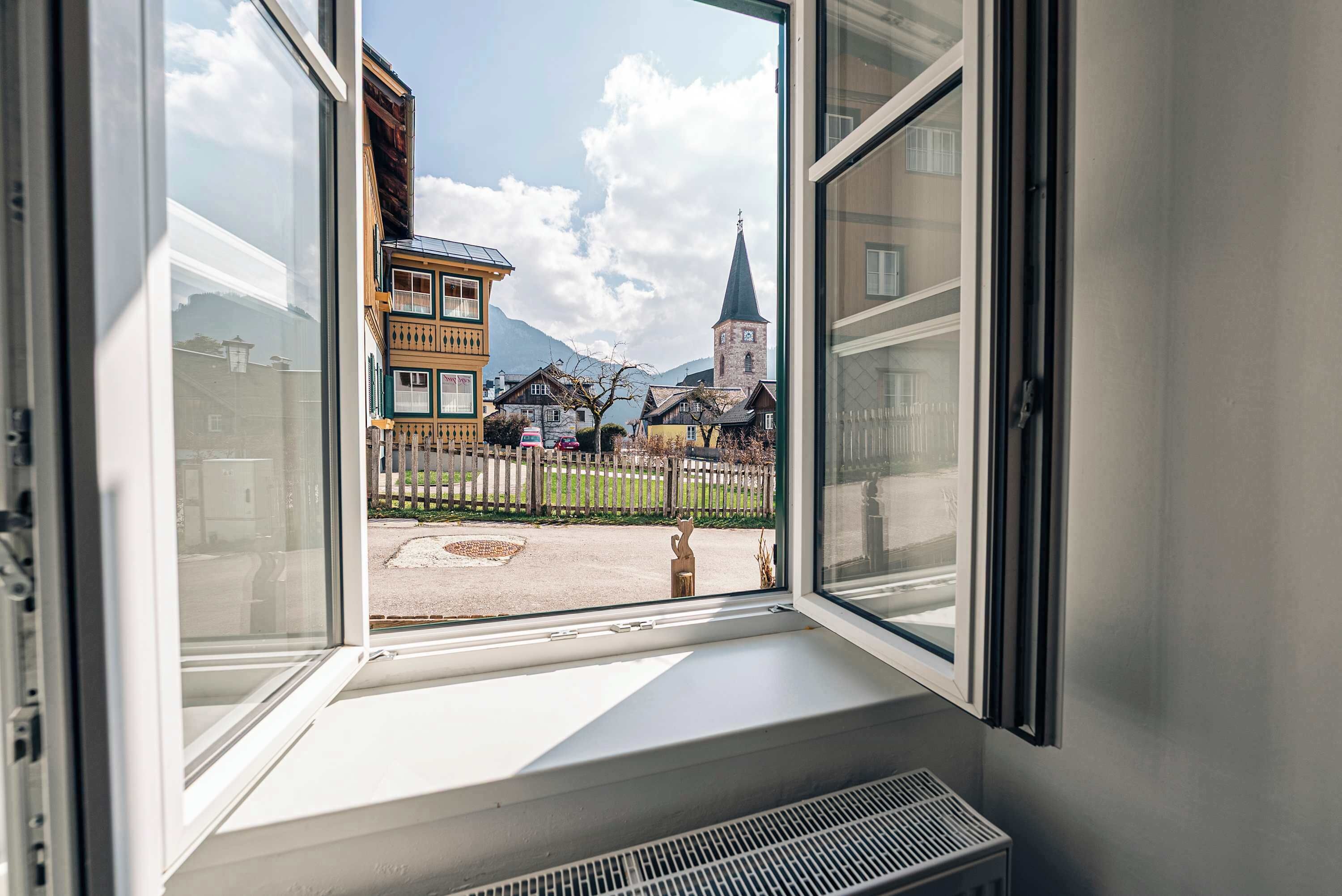 Ein Fenster mit Blick auf Gebäude und einen Kirchturm.