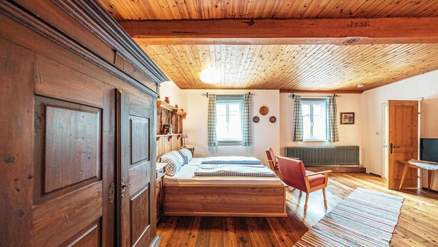 Een kamer met houten lambrisering, een bed, een stoel en een radiator.