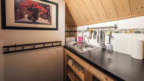 Een keuken met een houten plafond, een gootsteen en een rek met keukengerei.