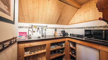 Eine Küche mit Holzausstattung, einer schwarzen Arbeitsplatte und einer Mikrowelle.