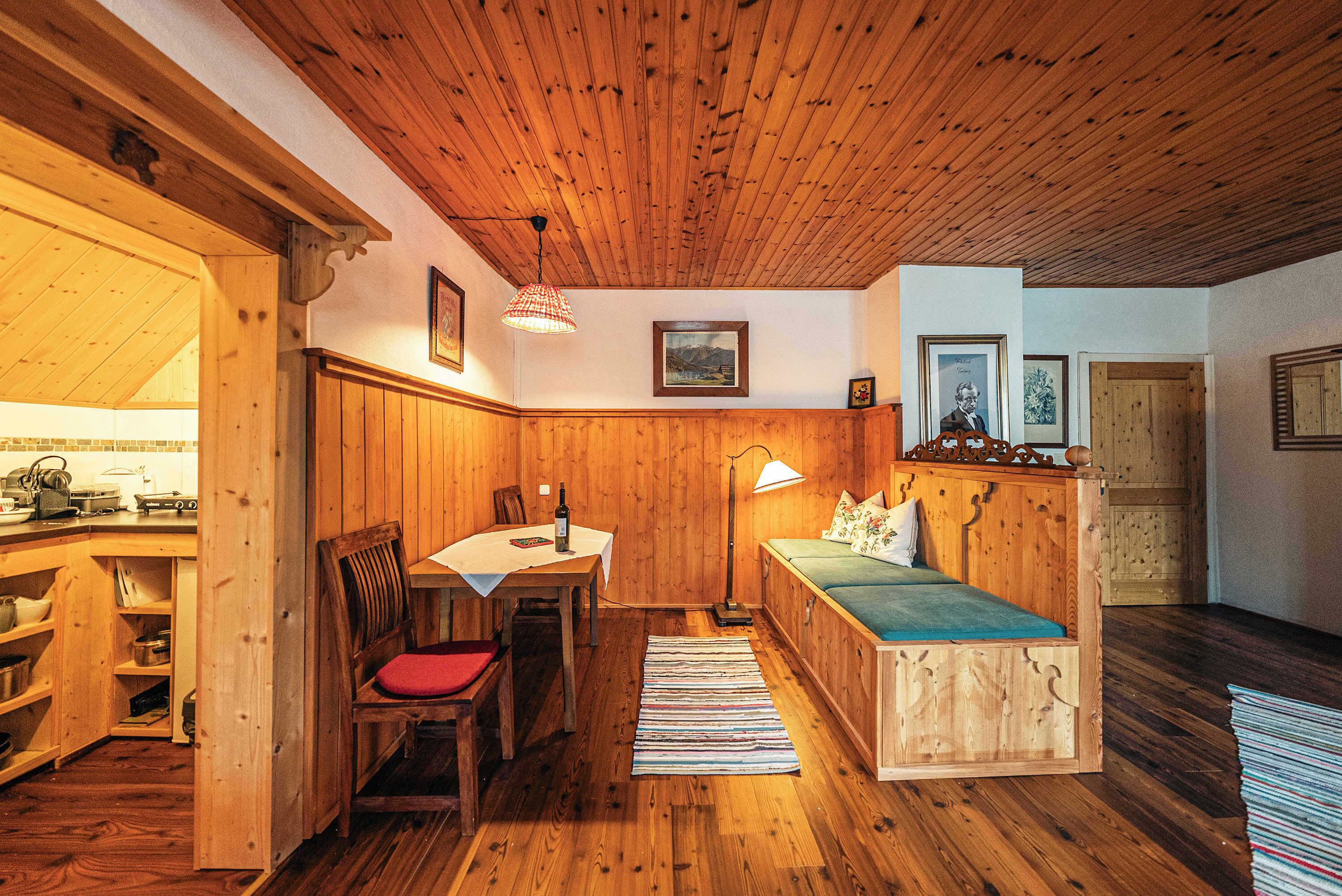 A wooden interior with a dining table, chairs, a bench, and a lamp.