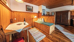 Een houten kamer met een tafel, een bank, een lamp en ingelijste foto’s aan de muur.