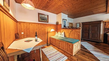 Ein Holzzimmer mit Tisch, Bank, Lampe und gerahmten Bildern an der Wand.