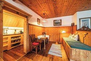 A wooden interior with a dining table, chairs, a sofa, and a kitchen area.