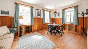 Una habitación con paneles de madera, una mesa de comedor, sillas, un sofá y una lámpara.