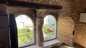 Ein Zimmer mit Steinwänden und zwei Rundbogenfenstern mit Blick auf einen Garten.