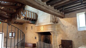 Ein rustikales Interieur mit Wendeltreppe, Kamin aus Stein und einer hölzernen Bank.