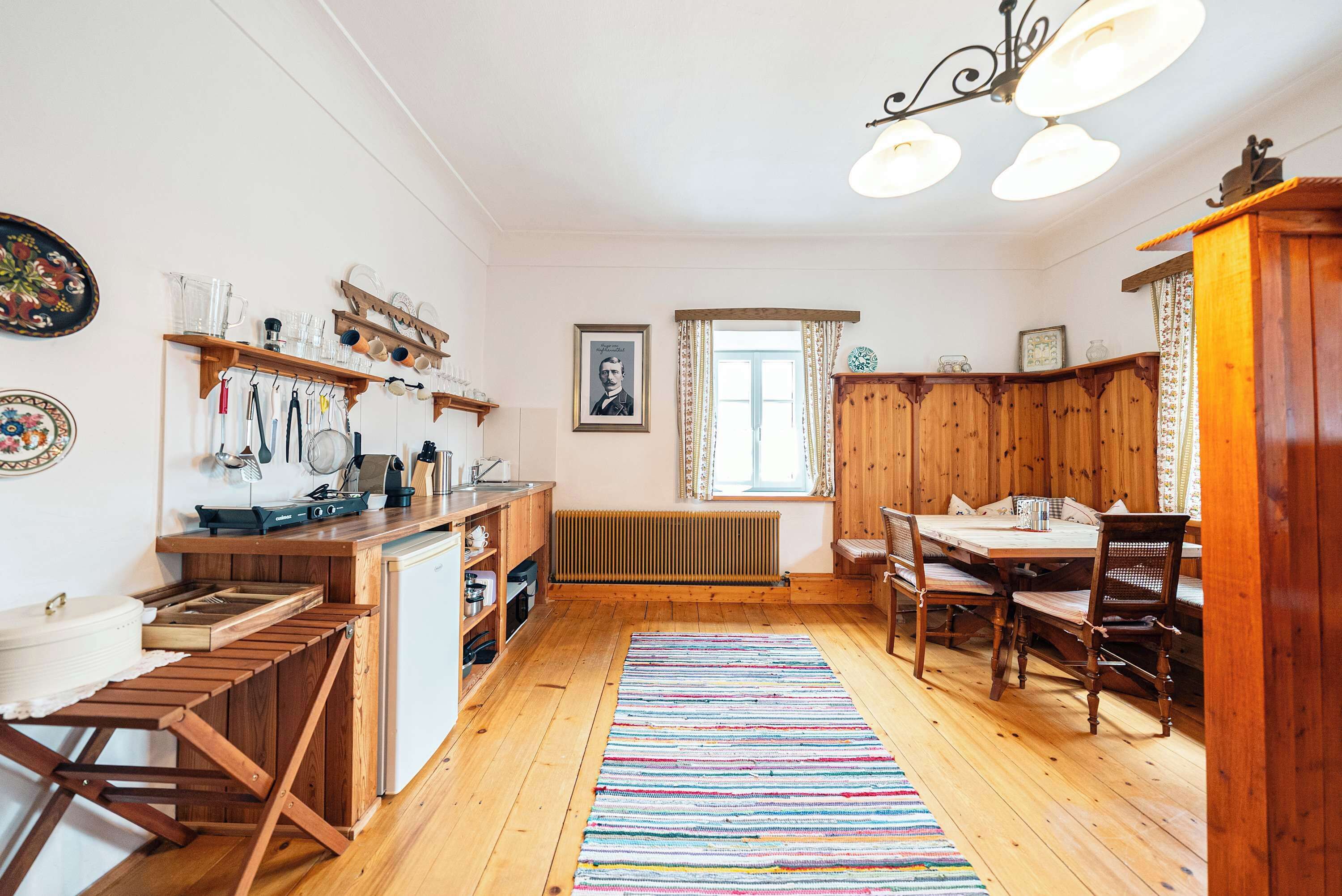 Una cocina con armarios de madera, una mesa de comedor y un tapete colorido.