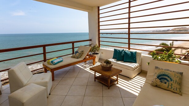Een balkon met uitzicht op zee, voorzien van een bank, stoelen en een tafel.
