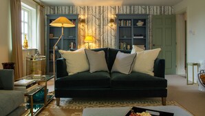 A living room with a dark green sofa, two lamps, and a bookshelf. - Sandstone 34 - sleeps 6 guests  in 3 bedrooms (Tattenhall, Cheshire)
