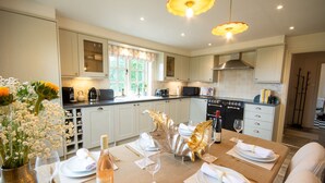 A modern kitchen with white cabinets, a dining area set for six with a table, and a decorative silver leaf centerpiece. - Sandstone 34 - sleeps 6 guests  in 3 bedrooms (Tattenhall, Cheshire)