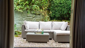 A wicker sofa with white cushions and a glass-top coffee table in a garden setting. - Sandstone 34 - sleeps 6 guests  in 3 bedrooms (Tattenhall, Cheshire)