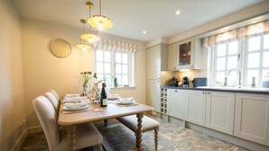 A modern kitchen with a dining table set for two, a clock on the wall, and a window with a view of the outdoors. - Sandstone 34 - sleeps 6 guests  in 3 bedrooms (Tattenhall, Cheshire)