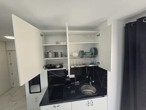 A compact kitchen with a black countertop, white cabinets, and a built-in sink. - Rental unit in Adeje · ★New · 1 bedroom · 1 bed · 1 bath (Adeje)