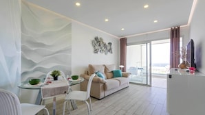 A modern living room with a sofa, a dining table with chairs, a glass coffee table, and a balcony with a view. - Rental unit in Adeje · ★New · 2 bedrooms · 2 beds · 2 baths (Adeje)